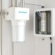 Close-up view of a modern full house water filtration system in a Houston utility room, with clear plastic pipes connecting to the main water line, captured in soft natural light for clarity and reliability.